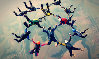 An aerial photo of a group of 12 skydivers holding arms and legs in a circle formation.